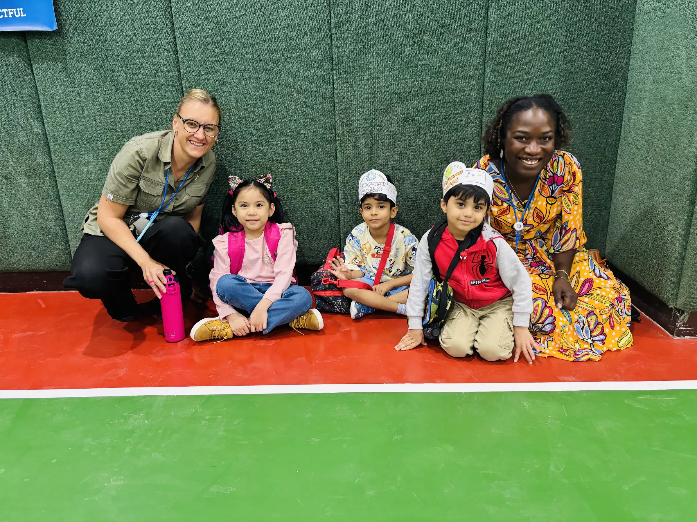 A teacher welcoming young preschoolers to their day