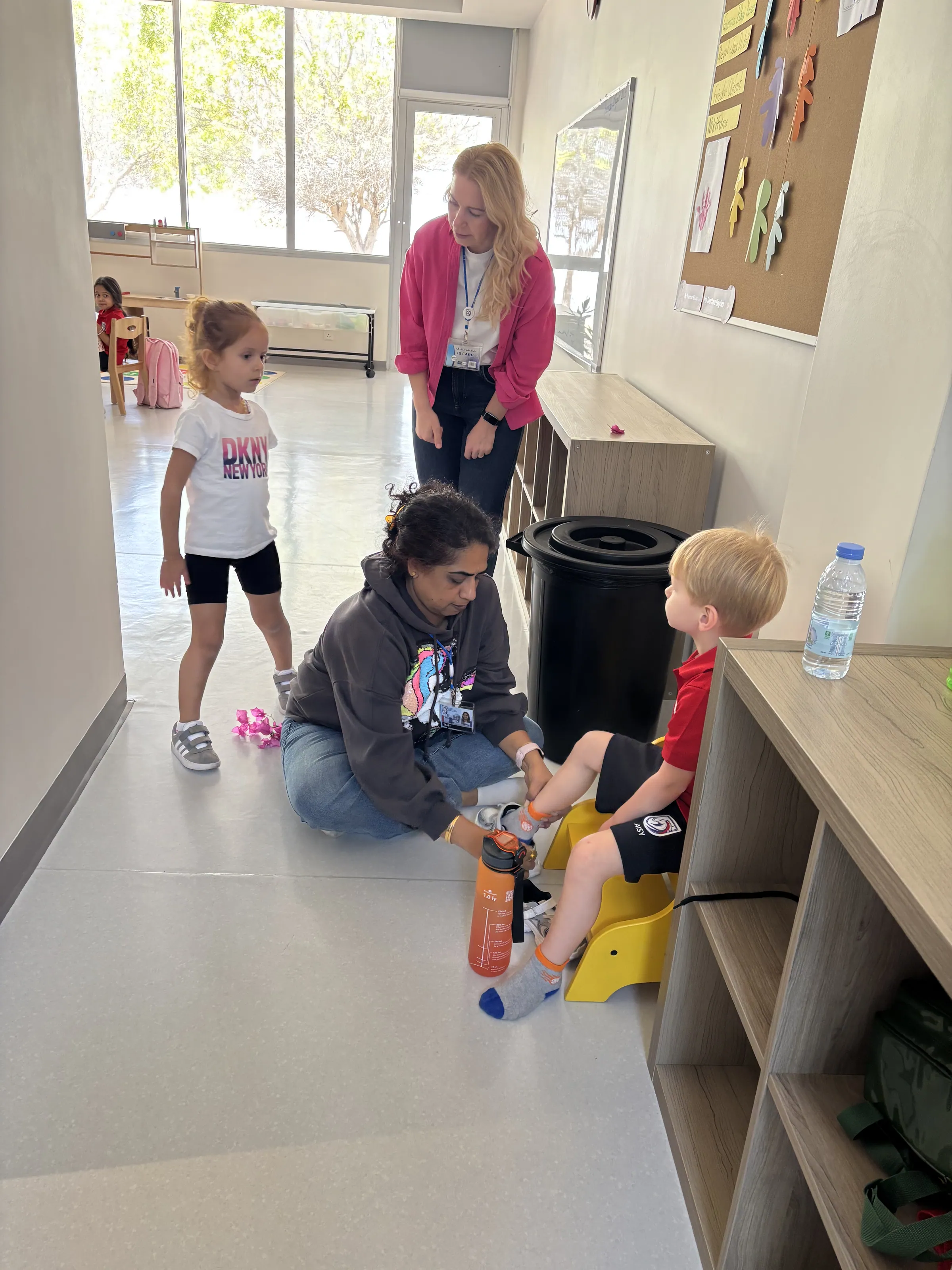 A teacher helping a young child get ready for play — gentle, individual care in the early years